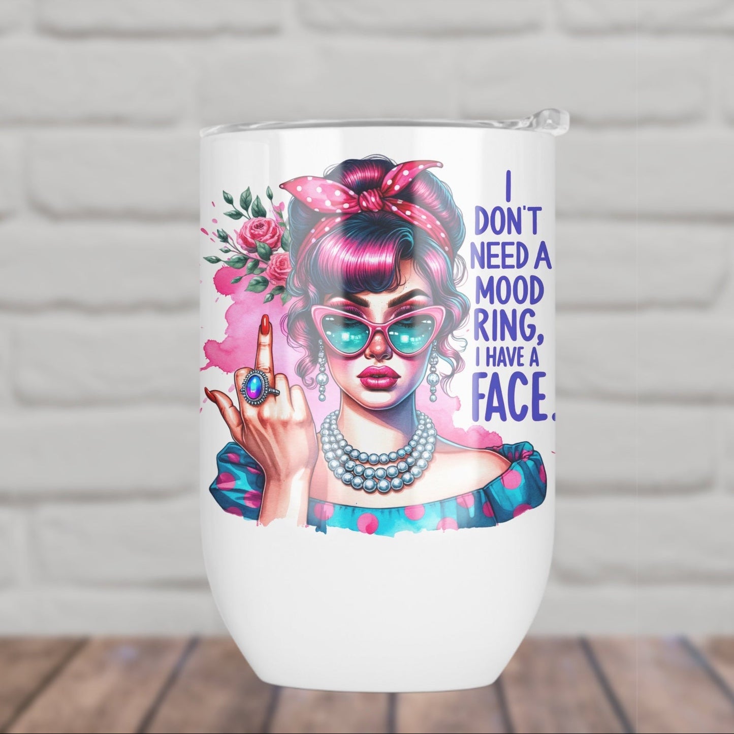 Tumbler with a colorful design of a woman with pink hair and sunglasses, and text 'I don't need a mood ring, I have a face.' against a white brick wall.