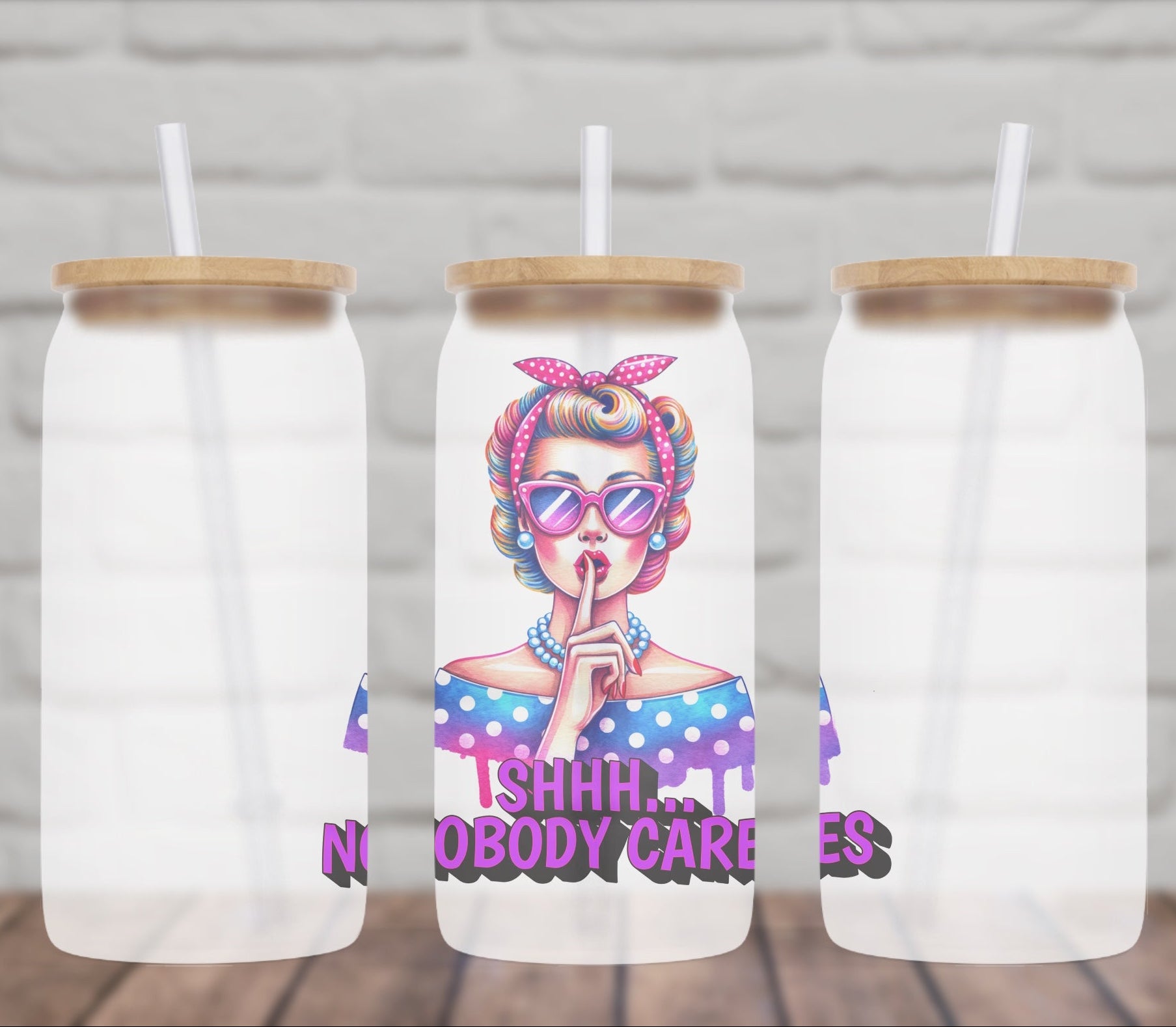 Three frosted glass tumblers with a design of a person with colorful hair and sunglasses, and text on a wooden surface.