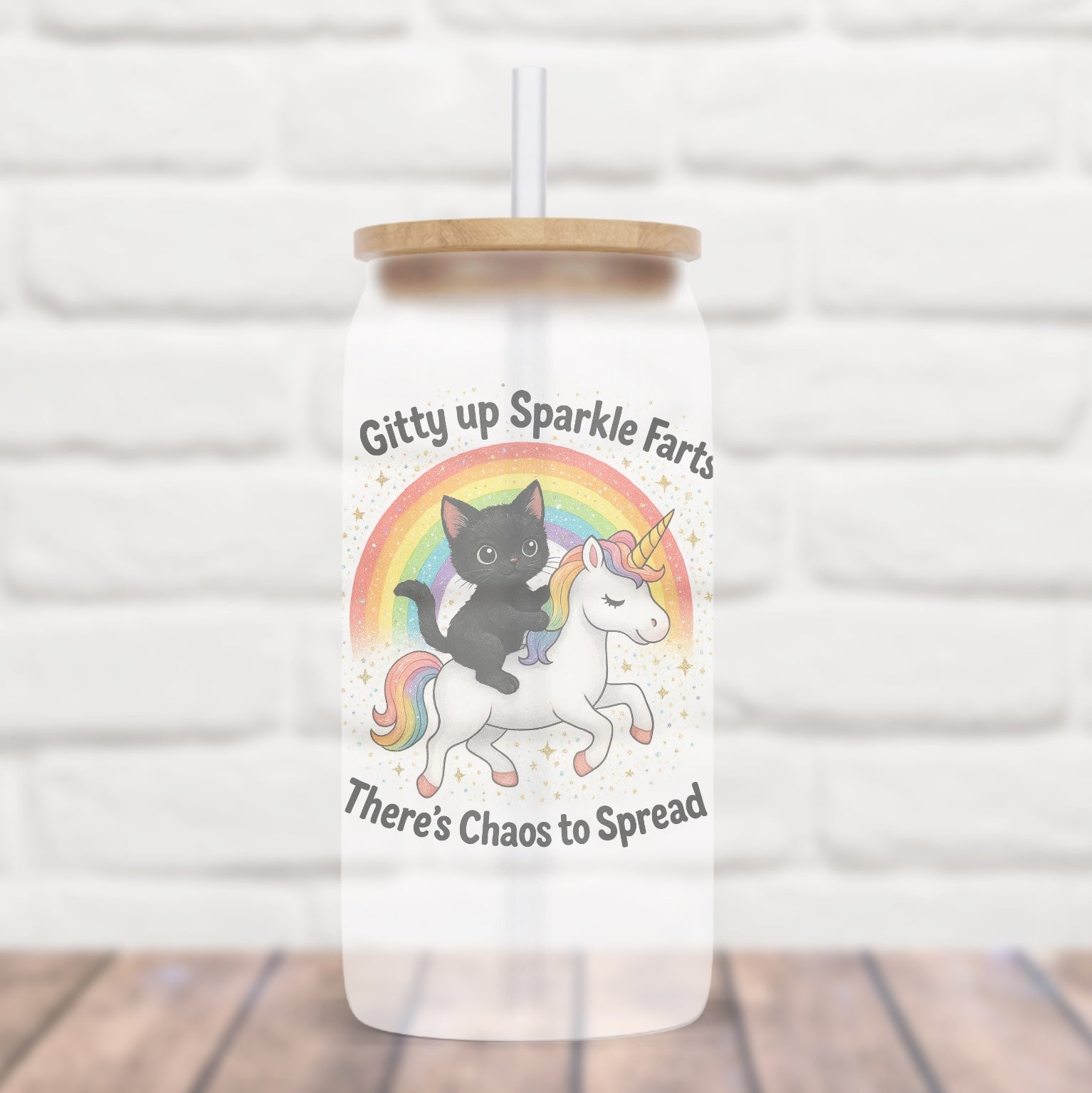 Clear tumbler with a lid featuring a black cat on a unicorn and text against a white brick wall.