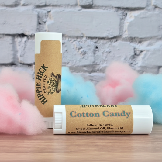 Two lip balm sticks with on a wooden surface and stone wall background.