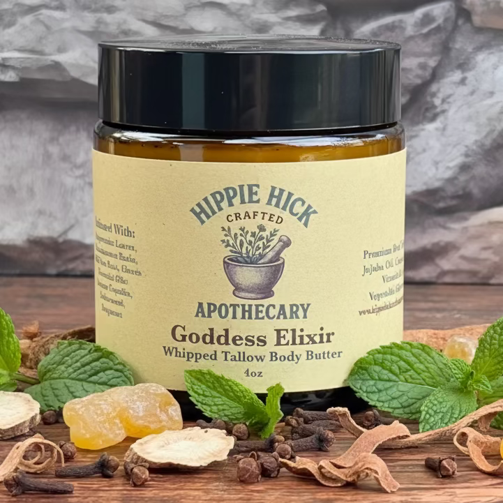 Jar of Hippie Hick Apothecary Goddess Elixir Whipped Tallow Body Butter on a wooden surface with stone wall background and herbs around the bottom