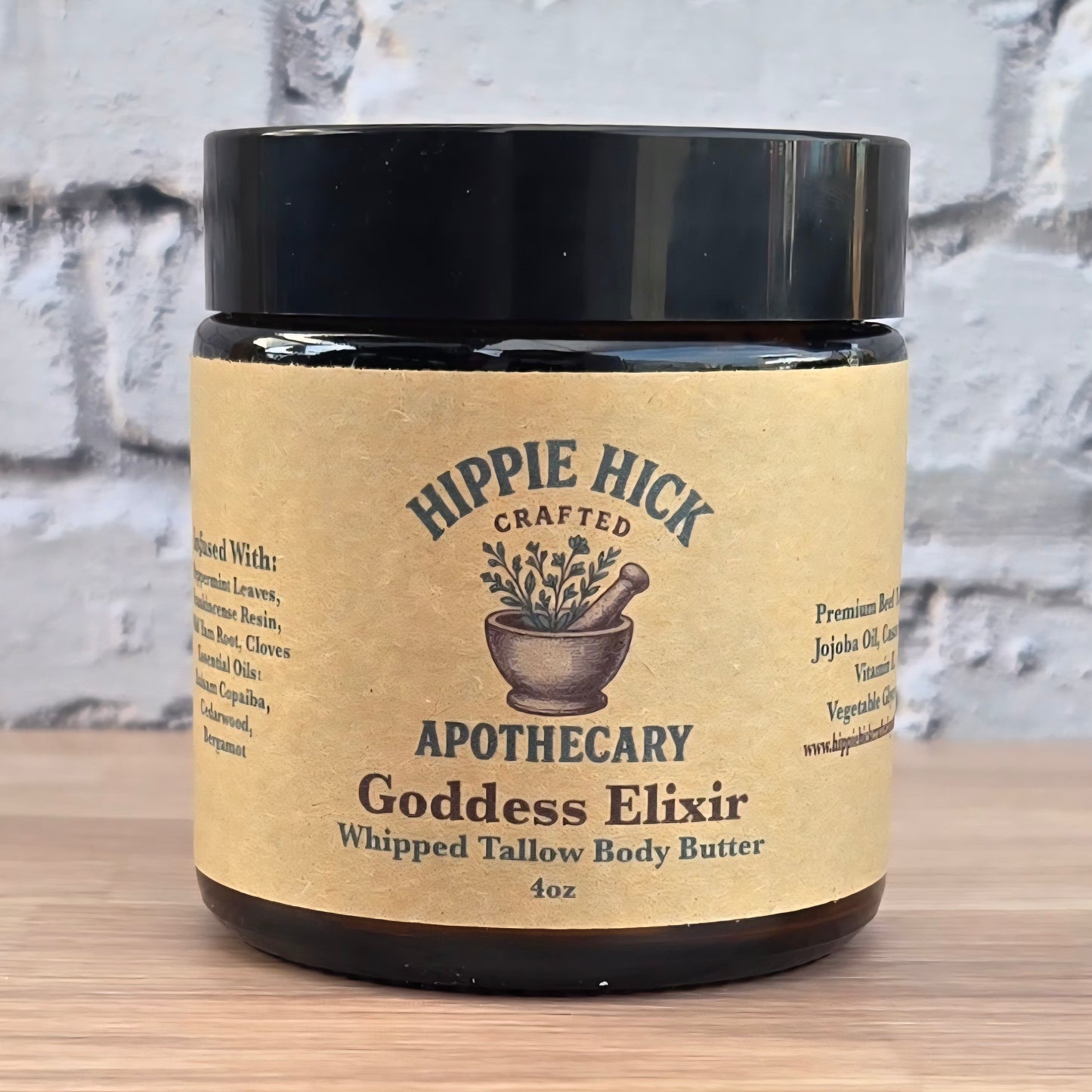 Jar of Hippie Hick Crafted Apothecary Goddess Elixir body butter on a wooden surface with a textured wall background.
