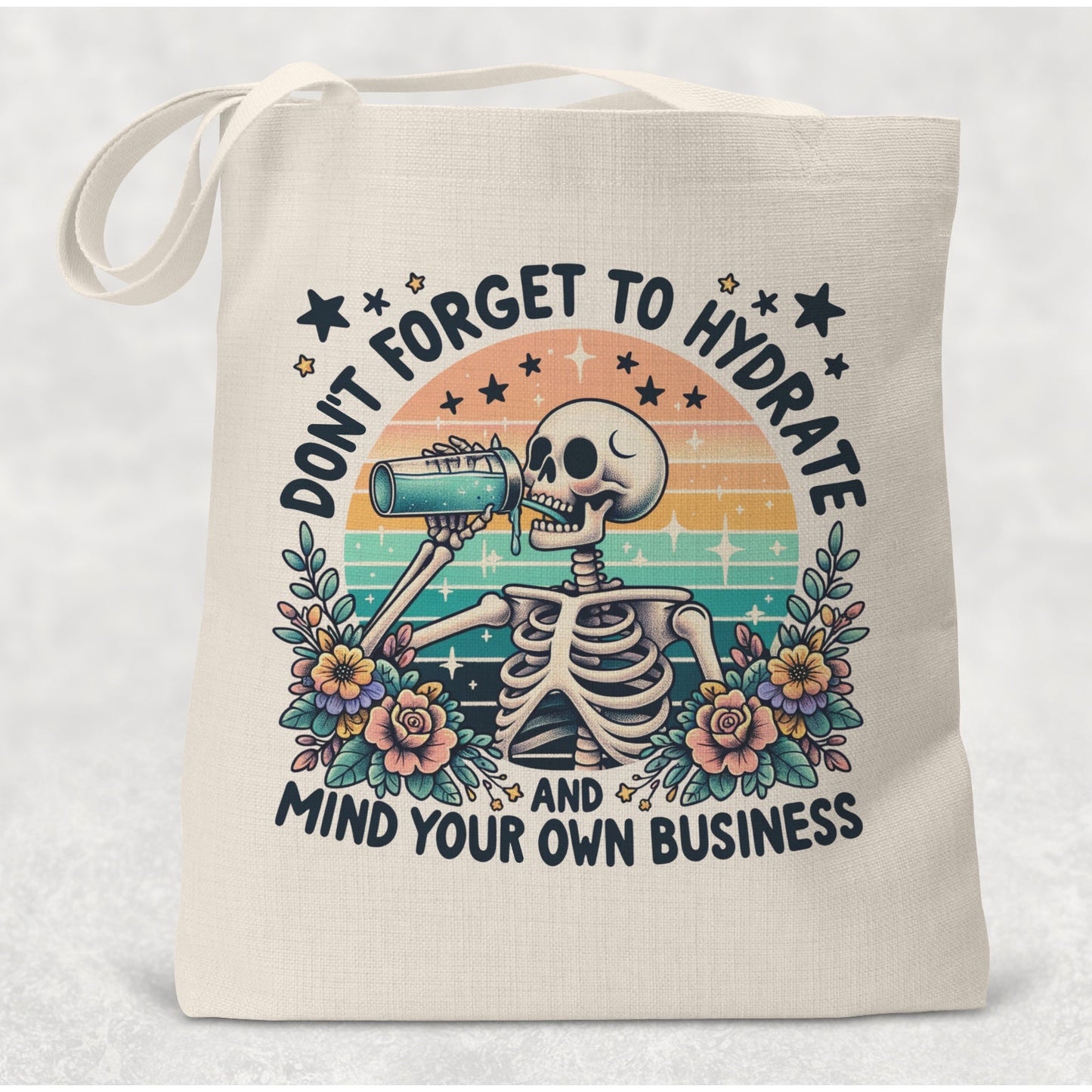 Tote bag with skeleton design and text 'Don't forget to hydrate and mind your own business' on a light background