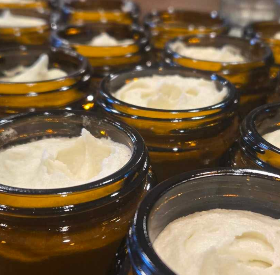 Multiple jars filled with a white substance, likely cream or yogurt, on a reflective surface.